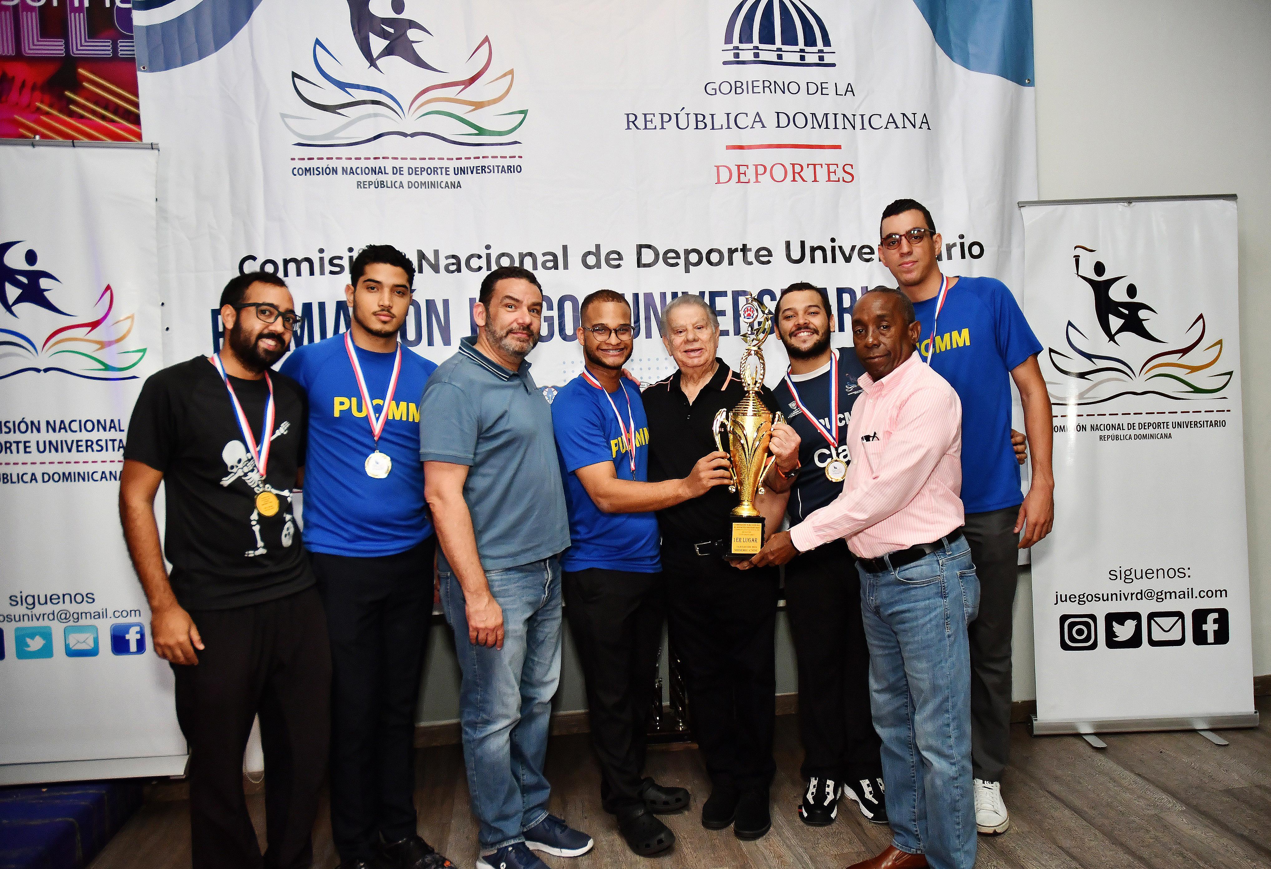 Roque García, presidente de la Comisión Nacional de Deportes Universitario y Director de Deportes Universitario de Miderec, premia al combinado de la Pontificia Universidad Católica Madre y Maestra (PUCMM), ganadora del torneo de boliche de los Juegos Universitarios en su versión 2024. Le acompaña en la premiación, Luis Francisco (Francis) Soto, presidente de la Asociación de Boliche del Distrito Nacional.